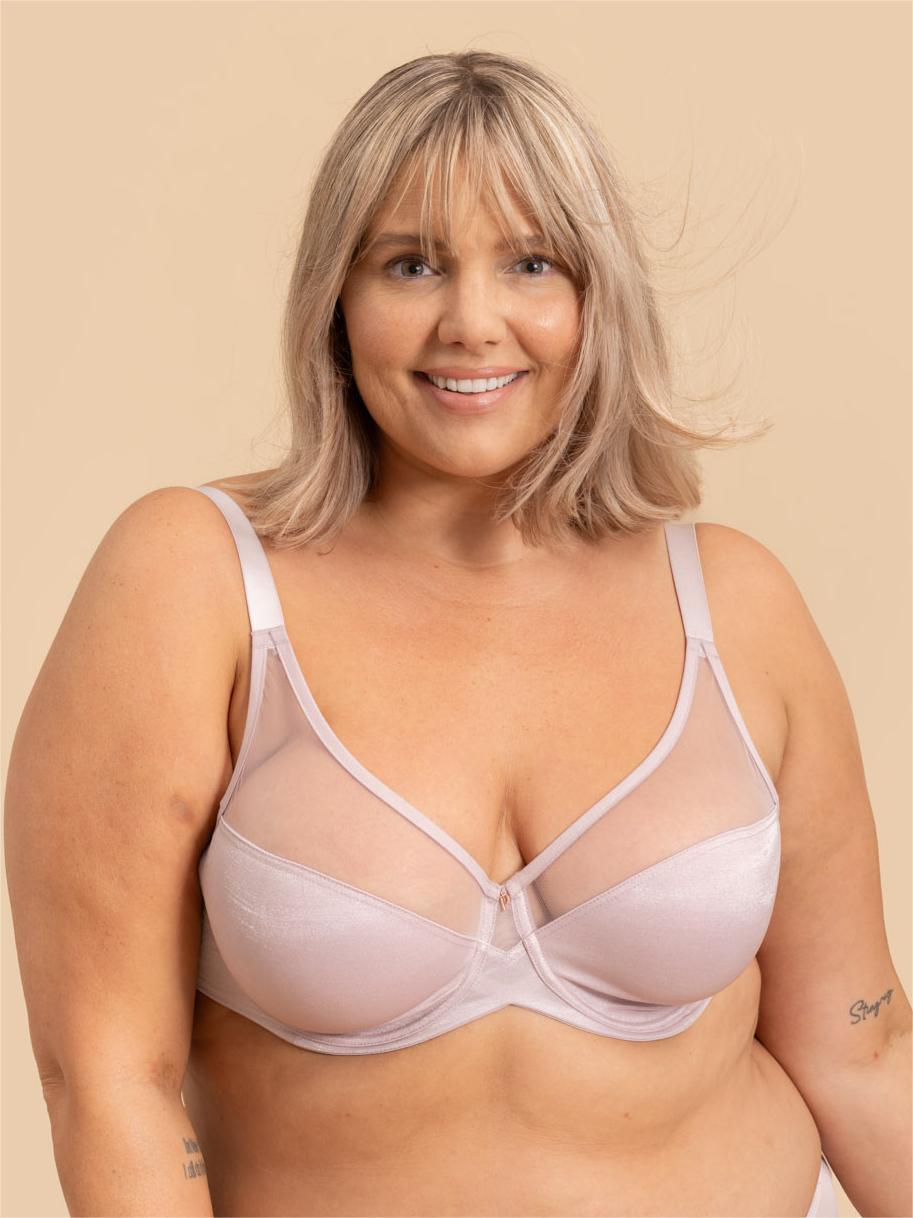 Woman wearing a light pink bra against a beige background