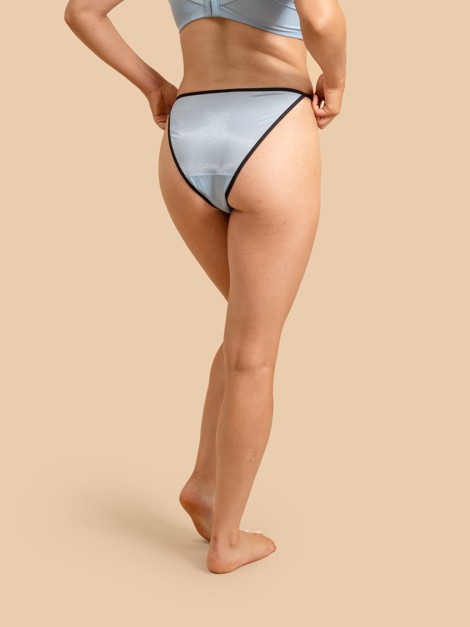 Person wearing light blue underwear on a beige background