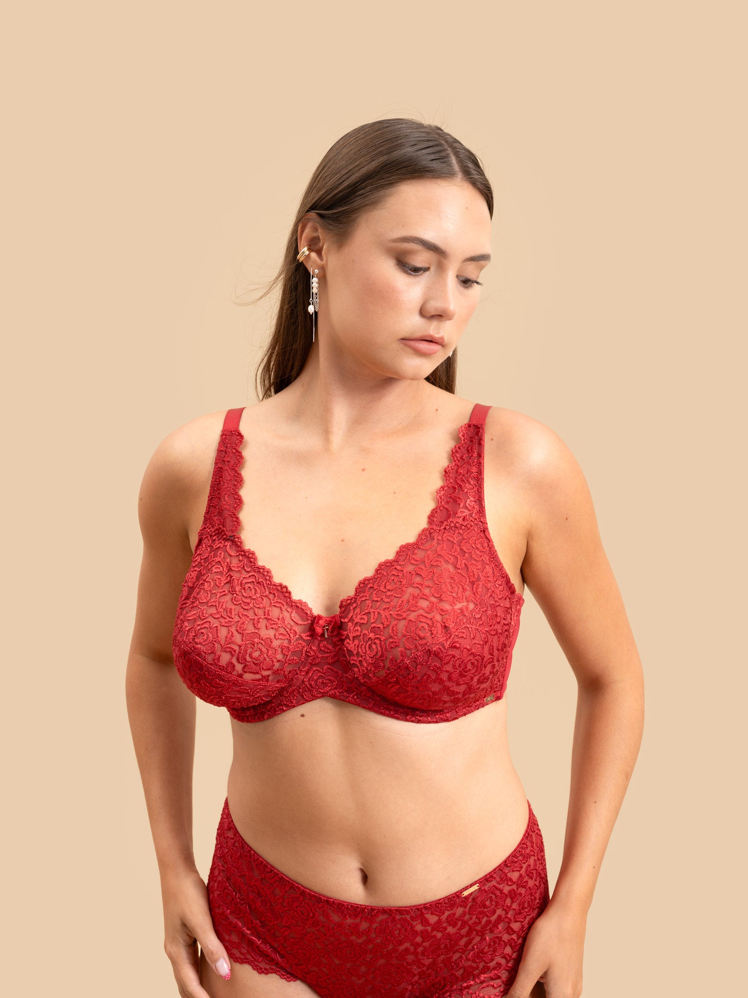 Woman wearing a red lace bra and panties set on a beige background