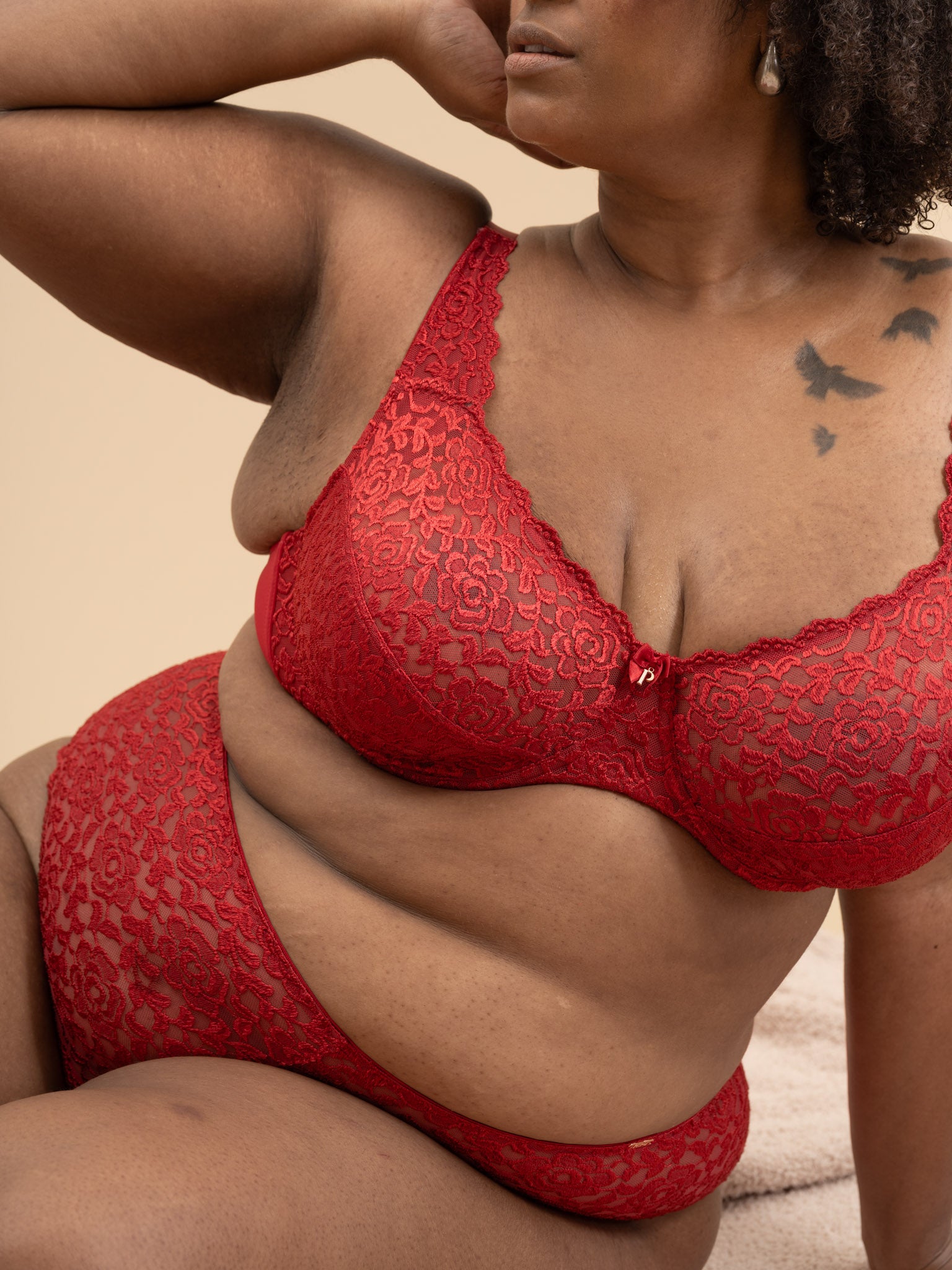 Woman wearing a red lace lingerie set against a beige background