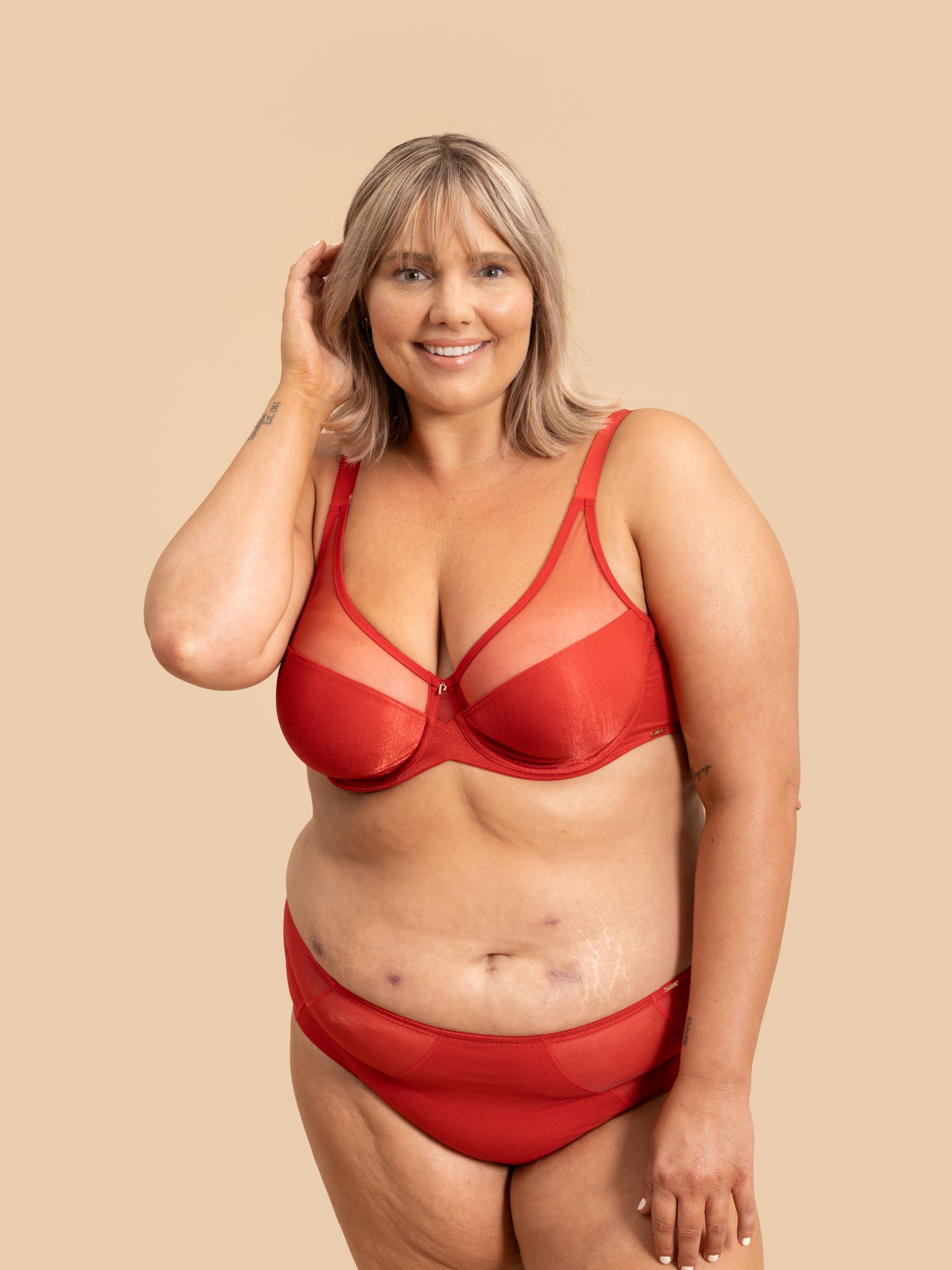 Woman wearing a red bra and underwear set against a beige background