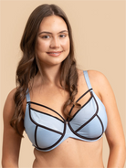 Woman wearing a light blue bra with black straps on a beige background