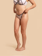 Person wearing a white bikini with black accents on a beige background