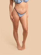 Person wearing a light blue bikini on a beige background