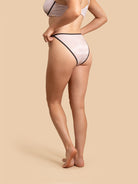 Person wearing white underwear with black accents on a beige background