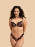 Woman wearing a leopard print bra and panties set on a beige background