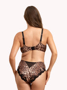A woman shown from the back wearing a leopard-print lingerie set with black straps and black lace trim, against a plain light background.