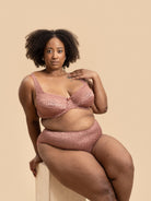 Woman wearing a pink lace lingerie set against a beige background
