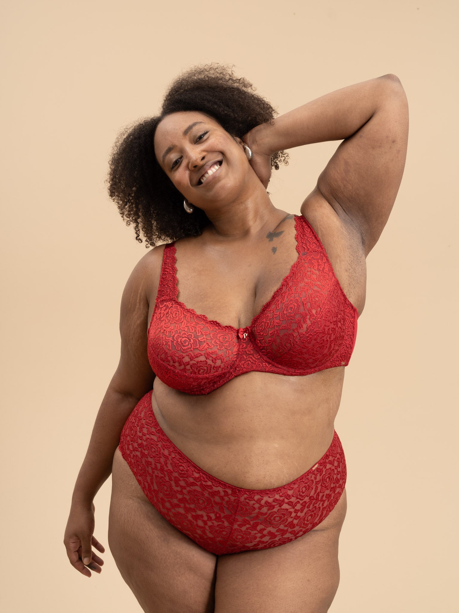Woman wearing a red lace lingerie set against a beige background
