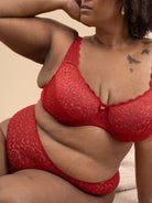 Woman wearing a red lace lingerie set against a beige background