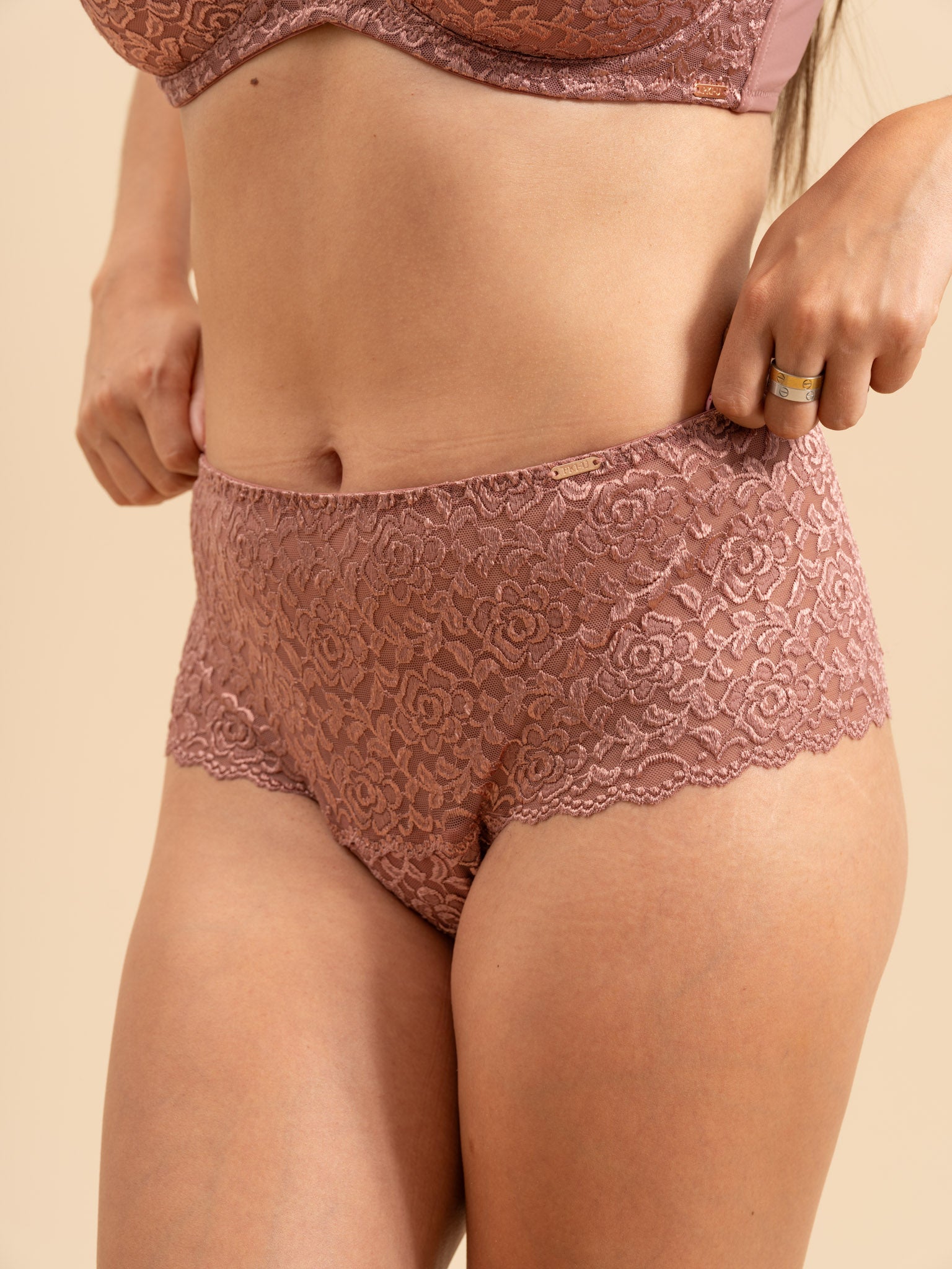 Lace underwear worn by a person on a beige background
