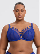 A plus-size model wearing a sapphire blue strappy mesh bra against a light gray studio background.