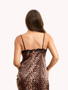 Woman wearing a leopard print slip dress against a beige background